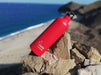 בקבוק שתיה לאקן תרמו פוטורה 350-750 מ"ל בצבע אדום מונח על סלע בים