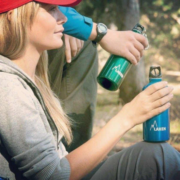 אישה מחזיקה בקבוק שתיה לאקן פוטורה בצבע כחול בטבע פתח צר