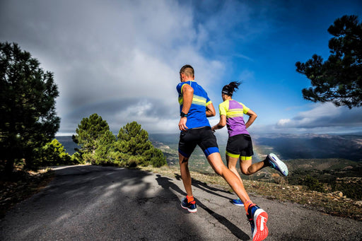 גבר ואישה רצים על הר עם נוף לבושים בגדי ספורט