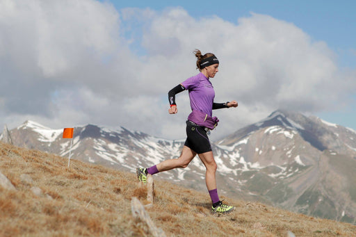 אישה רצה במורד הר עם גרבי קומפרשיין לריצות שטח ארוכות, גובה קלאסי H5 לורבל Gravity | נשים