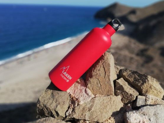 בקבוק שתיה לאקן תרמו פוטורה 350-750 מ"ל בצבע אדום מונח על סלע בים