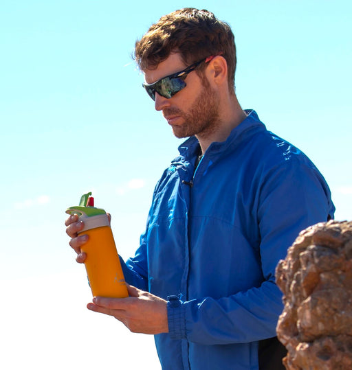 גבר עם משקפי שמש מחזיק בקבוק שתיה לאקן תרמו סאמיט ספורט עם פקק קשית 350-1000 מ"ל בצבע כתום