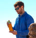 גבר עם משקפי שמש מחזיק בקבוק שתיה לאקן תרמו סאמיט ספורט עם פקק קשית 350-1000 מ"ל בצבע כתום